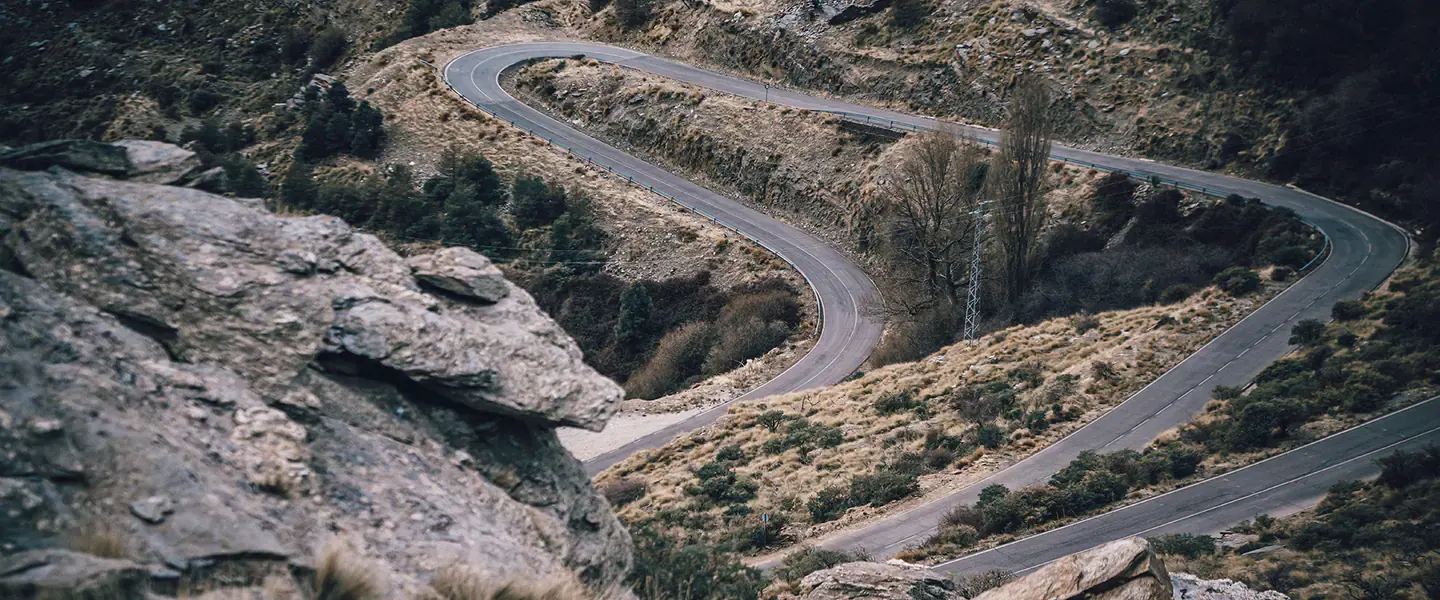 Carretera sinuosa entre montañas, vista desde un mirador rocoso